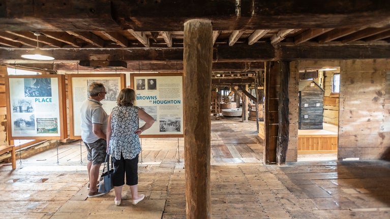 Visitors inside the eighteenth-century mill at Houghton Mill and Waterclose Meadows, Cambridgeshire